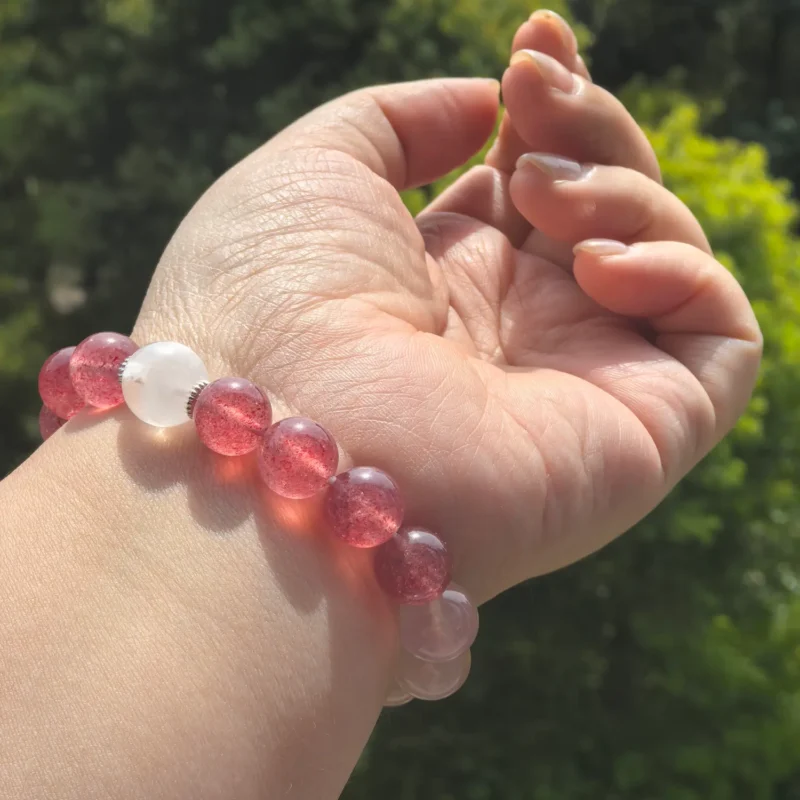 Pink and clear quartz beads held in bright outdoor light